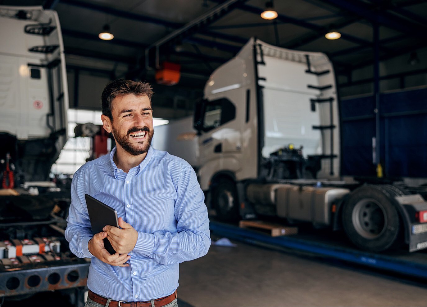 Man standing in shop by semi trucks