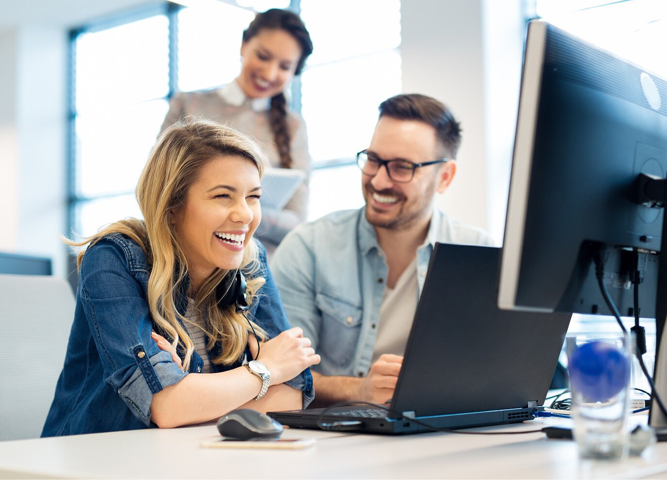 team members smiling at computer